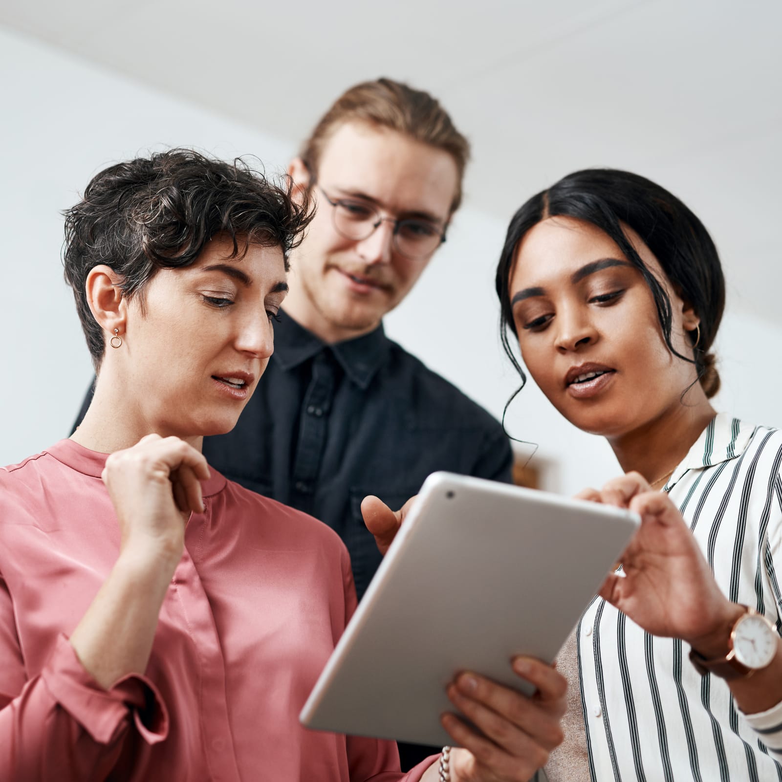 Group of three people looking at a tablet