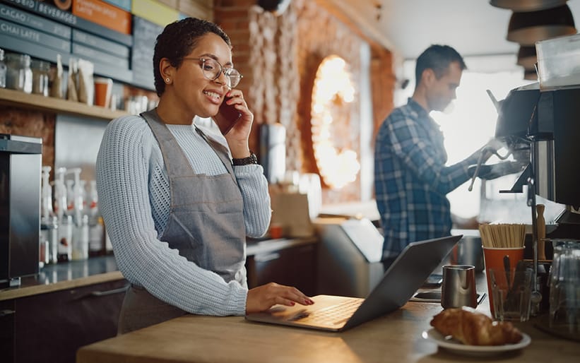 Woman on phone while looking at laptop