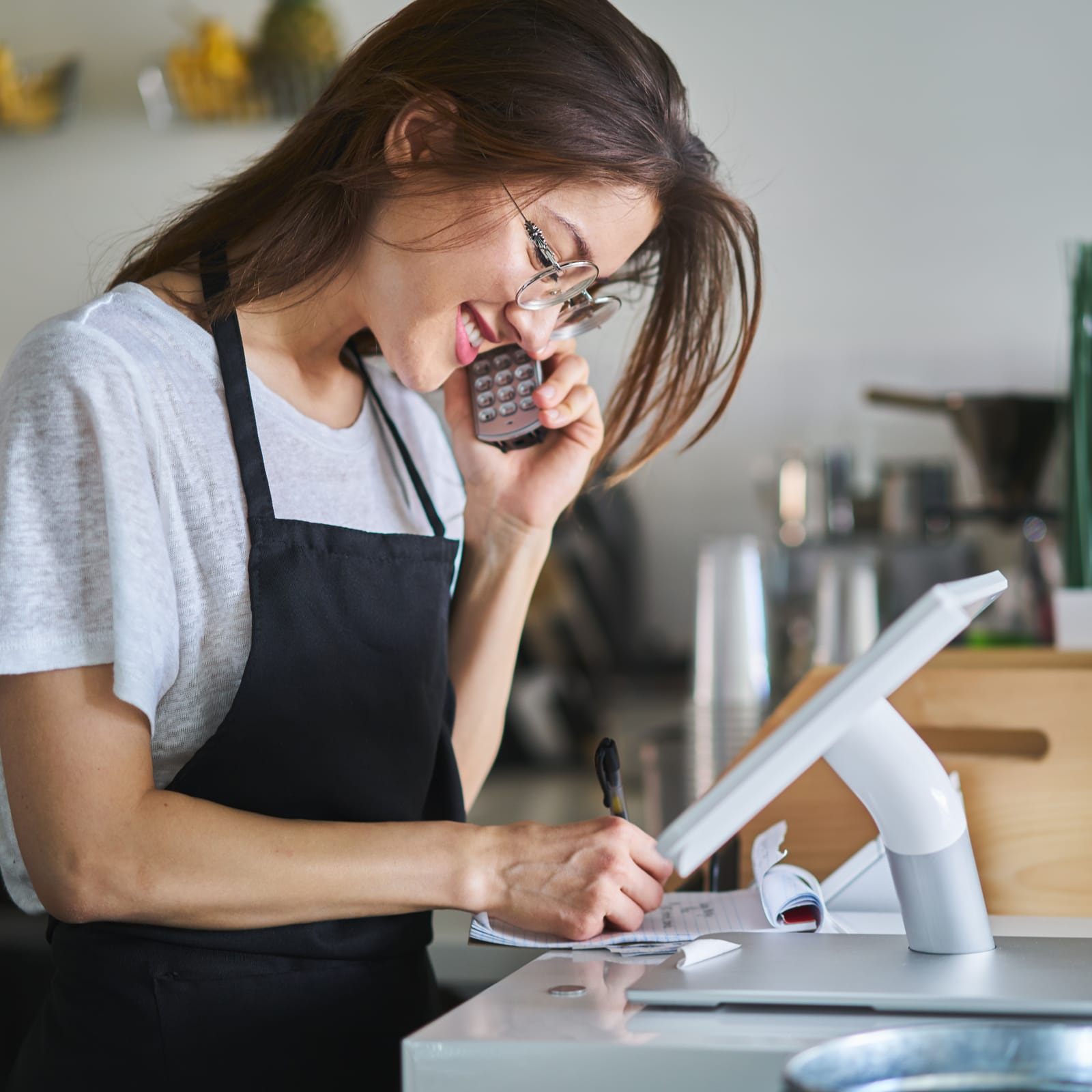 Woman on phone while writing on a notepad